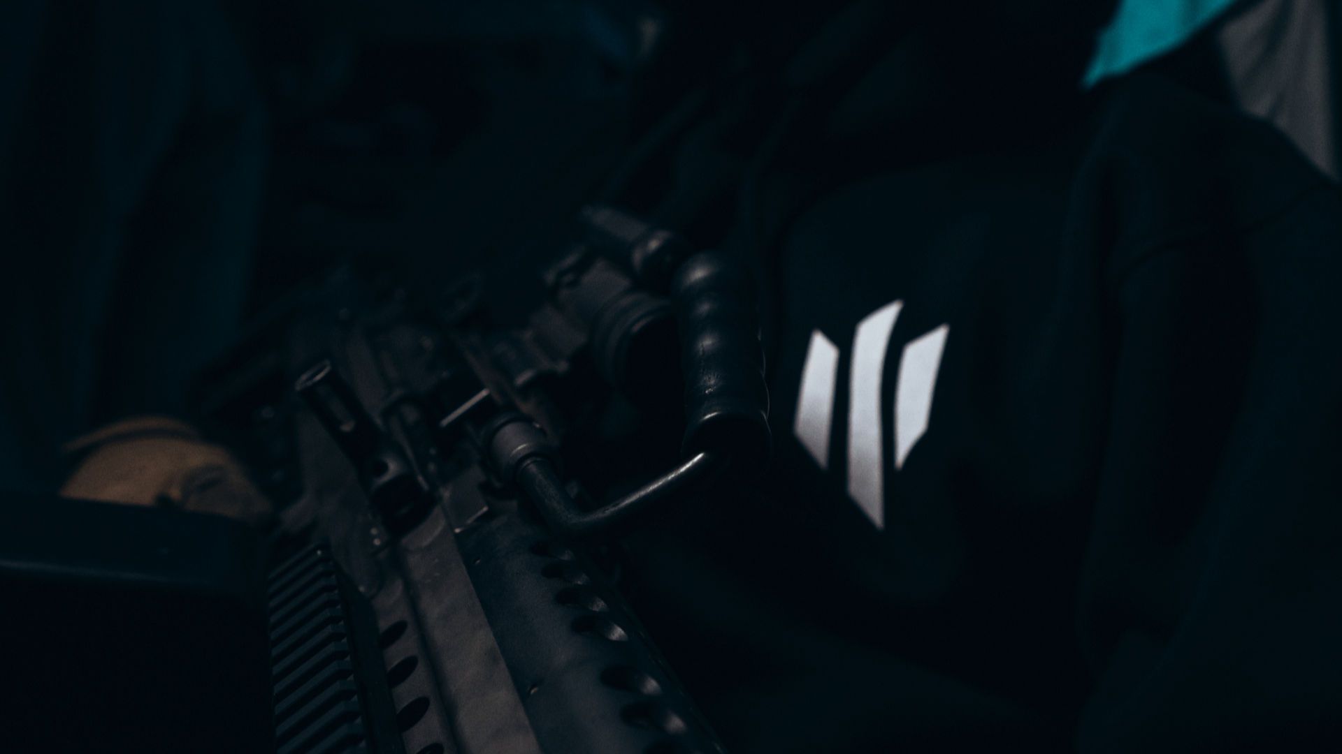 Людина у толстовці з логотипом КАРА на тлі військового обладнання